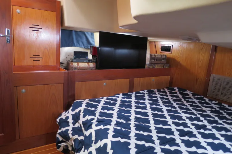 Slide: The Image of Cozy cabin interior of 2000 Hunter Legend 410 sailboat with patterned bedding and wooden cabinetry. - 13