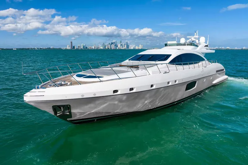 Slide: The Image of Luxurious 2016 Mangusta 94 yacht cruising on turquoise waters with city skyline backdrop. - 20