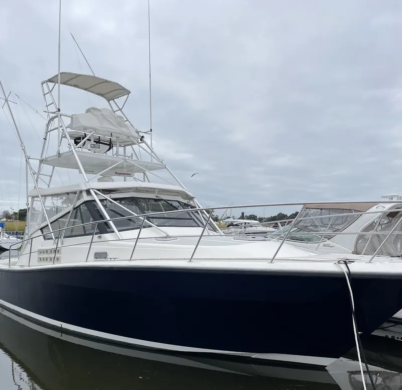 Slide: The Image of A 1993 Rampage Express Sportfish with a blue hull and white superstructure, docked in a marina. - 5