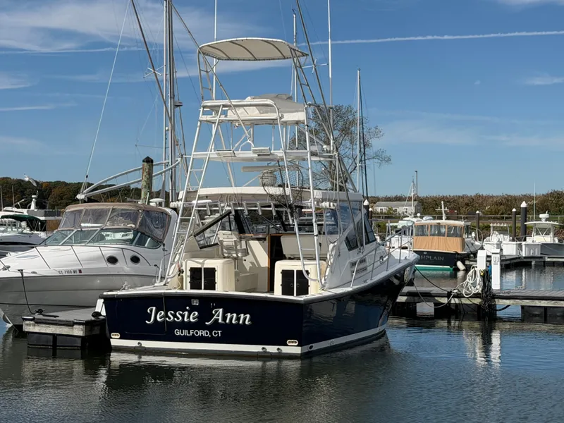 Slide: The Image of A 1993 Rampage Express Sportfish boat in the harbor, featuring a blue hull and tall helm. - 11