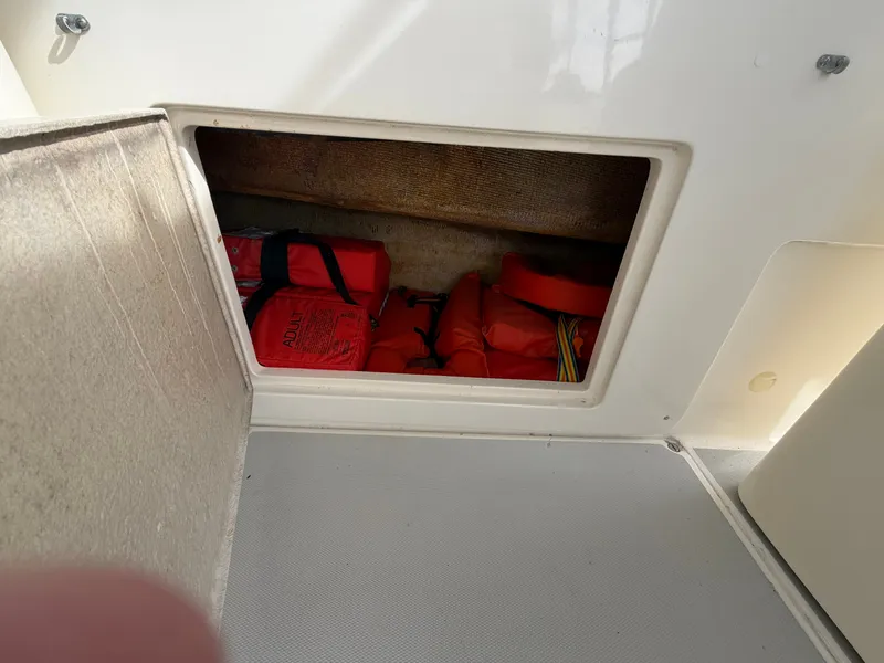 Slide: The Image of A storage compartment on a boat containing several red life jackets. - 43