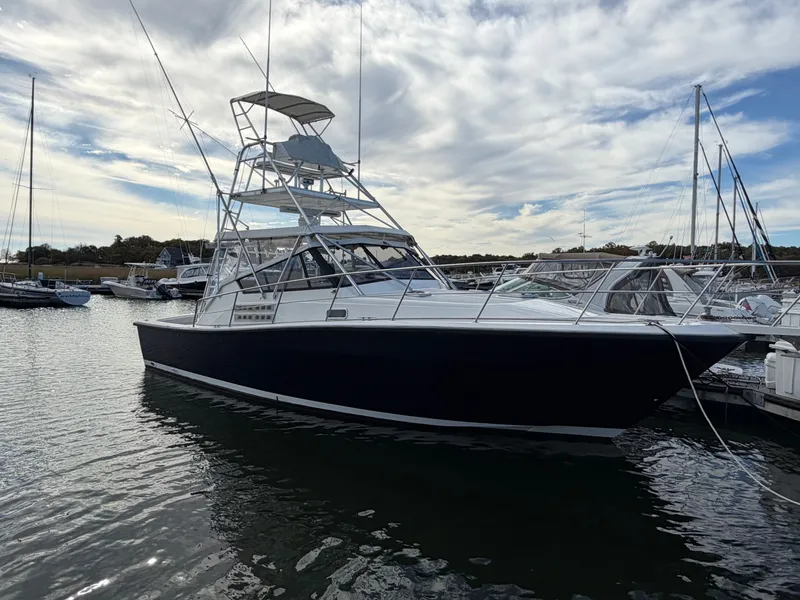 Slide: The Image of A 1993 Rampage Express Sportfish boat is docked in the water, surrounded by other boats and a cloudy sky. - 2