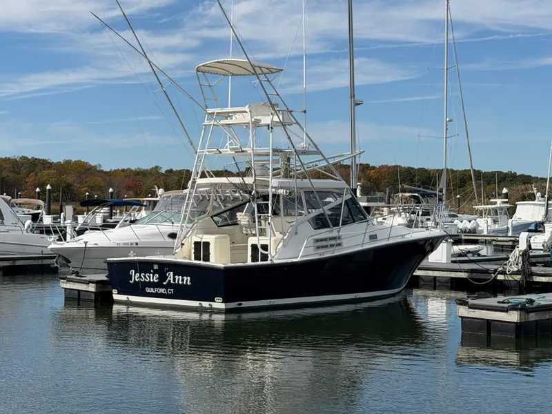 Slide: The Image of A 1993 Rampage Express Sportfish docked in a marina. It features a dark hull and elevated helm. - 8