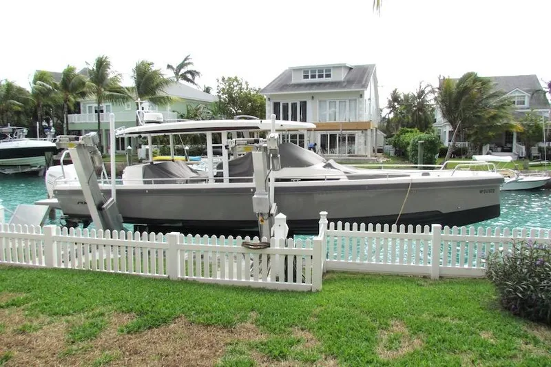 Slide: The Image of 2018 Axopar 37 Sun-Top boat docked by waterfront homes, surrounded by palm trees. - 1