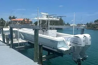 Slide: The Image of 2002 Intrepid 323 Cuddy boat docked with dual outboard engines in a sunny marina. - 1