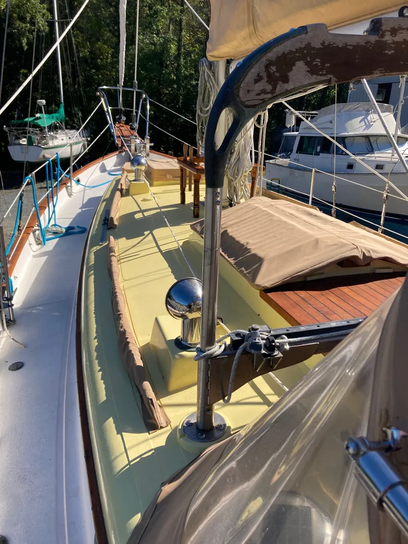 Slide: The Image of A 1983 Union Cutter with a yellow deck and brown covers, docked in a calm harbor. - 3
