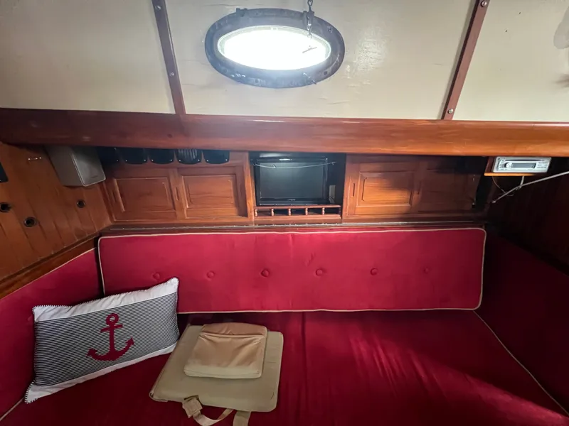 Slide: The Image of Interior of a 1983 Union Cutter with red sofa and porthole. - 17
