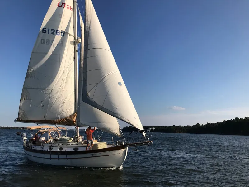 Slide: The Image of A sailboat with white sails glides on calm water under a blue sky. - 25