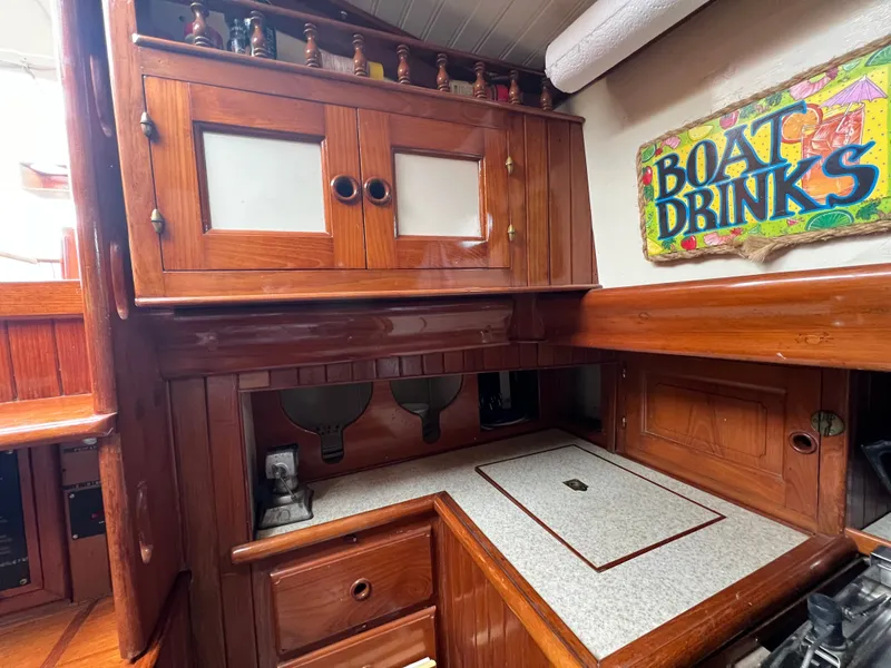 Slide: The Image of Wood-paneled galley with cabinets and countertop, decorated with a "Boat Drinks" sign. - 13