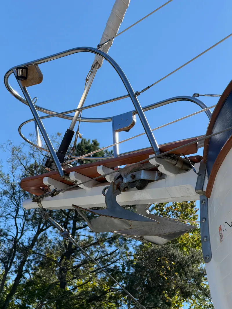 Slide: The Image of Bow of a sailboat with anchor and railing, set against a blue sky and trees. - 5
