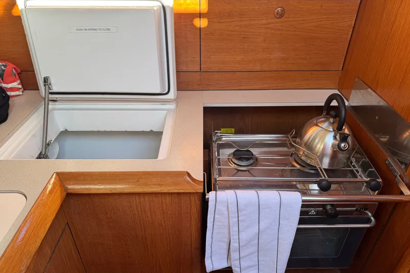 Slide: The Image of Galley of 2004 Jeanneau Sun Odyssey 37 with stove, kettle, and open storage compartment. - 5
