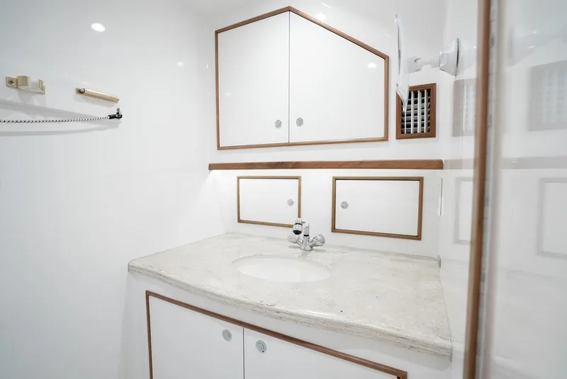 Slide: The Image of A sleek bathroom with a white vanity, mirror, and wood trim. - 50