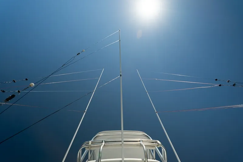 Slide: The Image of View from below of a sportfishing boat's outriggers against a clear sky. - 25