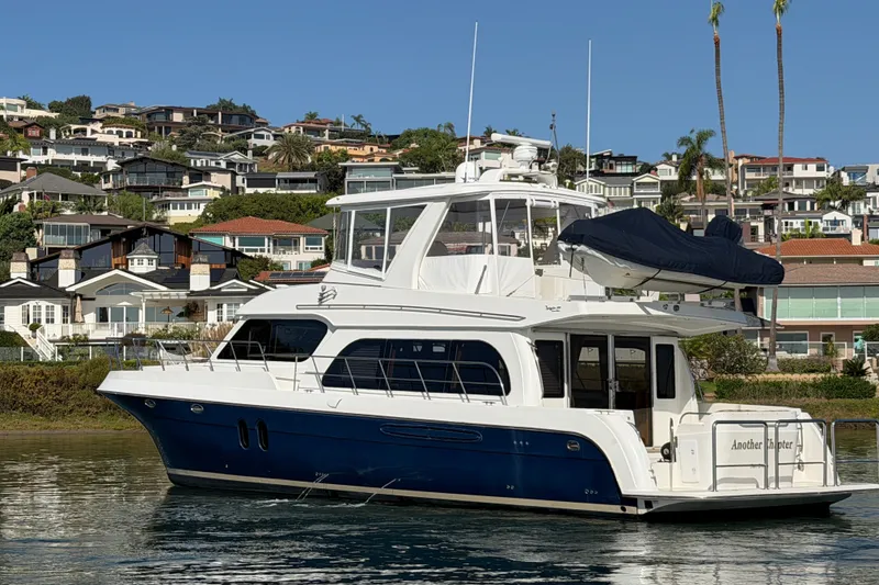 Slide: The Image of 2009 Navigator 5800 Pilothouse MY yacht docked near coastal homes. - 2