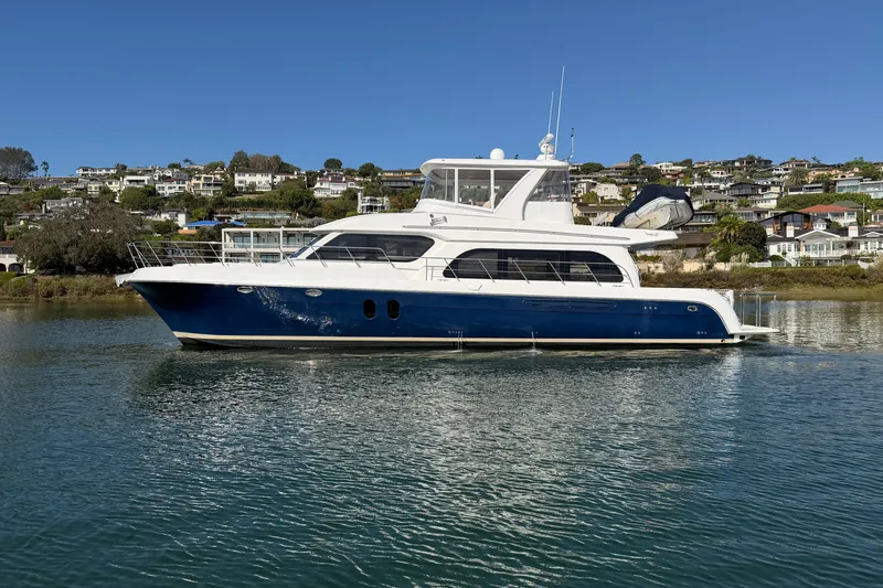 Slide: The Image of 2009 Navigator 5800 Pilothouse MY yacht on calm water, with scenic coastal backdrop. - 1