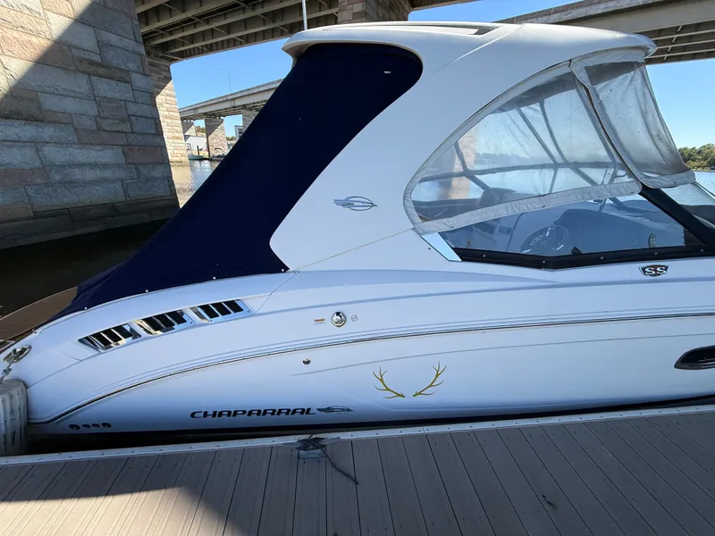 Slide: The Image of A 2018 Chaparral 337 SSX with a blue canopy, docked under a bridge. - 1