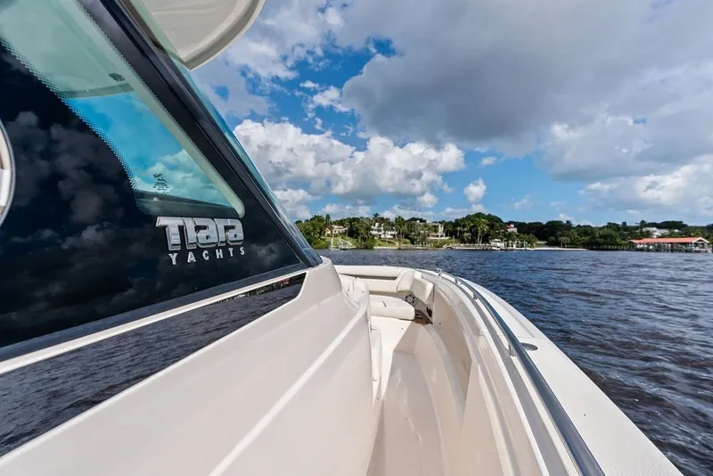 Slide: The Image of 2024 Tiara Yachts 38 LS cruising on a sunny day with scenic shoreline views. - 29