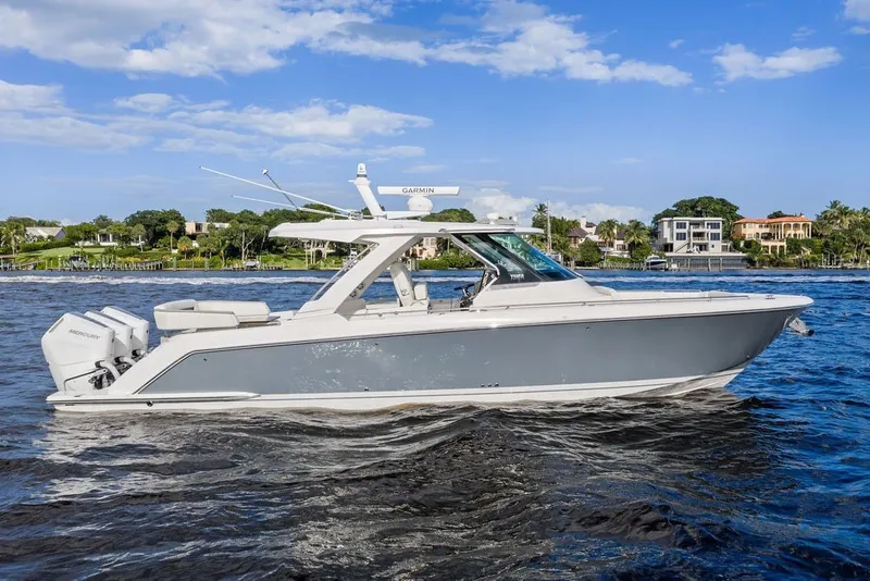 Slide: The Image of 2024 Tiara Yachts 38 LS cruising on a sunny day with waterfront homes in the background. - 15