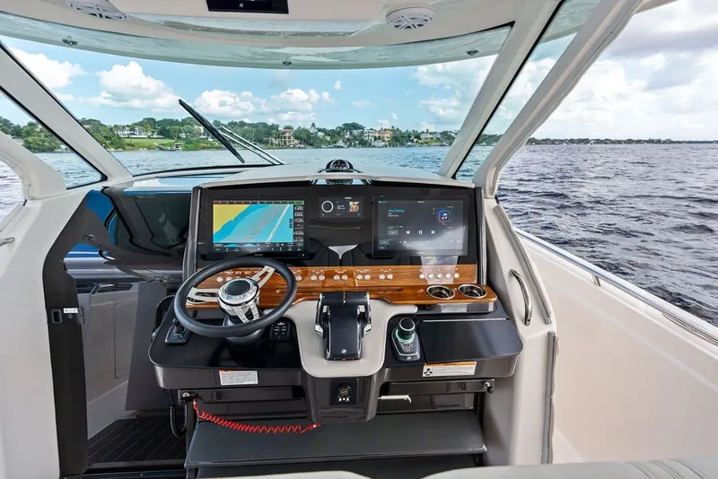 Slide: The Image of 2024 Tiara Yachts 38 LS helm with advanced navigation displays and steering wheel on open water. - 48