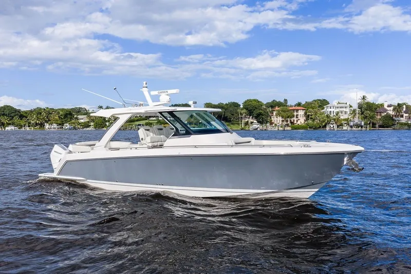 Slide: The Image of 2024 Tiara Yachts 38 LS cruising on a sunny day with scenic waterfront backdrop. - 13
