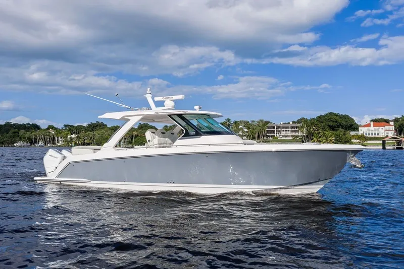 Slide: The Image of 2024 Tiara Yachts 38 LS cruising on a sunny day with scenic shoreline backdrop. - 4