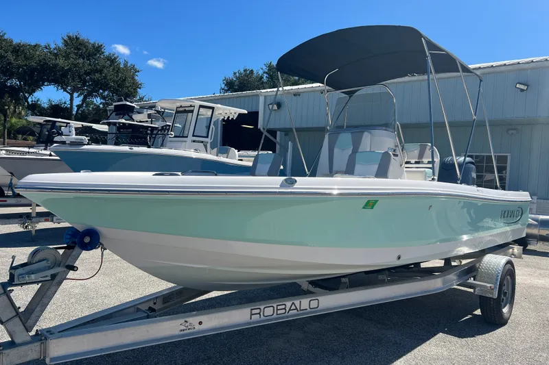 Slide: The Image of 2024 Robalo 206 Cayman boat on trailer, parked outdoors under clear blue sky. - 6