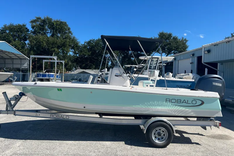 Slide: The Image of 2024 Robalo 206 Cayman boat on trailer, parked outdoors under clear blue sky. - 1