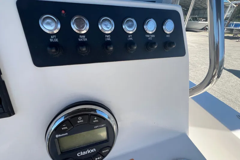 Slide: The Image of Control panel of 2024 Robalo 206 Cayman boat with switches and Clarion audio system. - 13