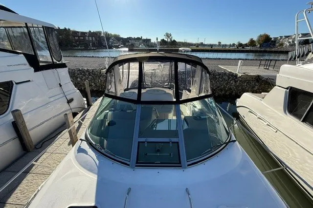Slide: The Image of 2000 Sea Ray 340 Sundancer docked between boats, with clear canopy and waterfront view. - 6