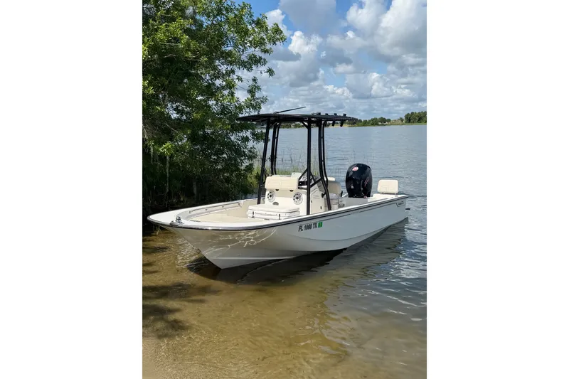 The Image of 2023 Boston Whaler 190 Montauk boat docked by a serene lake under a cloudy sky. - 0