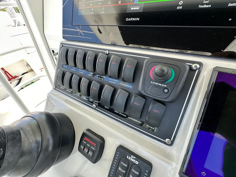 Slide: The Image of Das Bild zeigt das Armaturenbrett eines Boston Whaler 380 Outrage von 2017 mit verschiedenen Schaltern und einem Garmin-Display. - 24