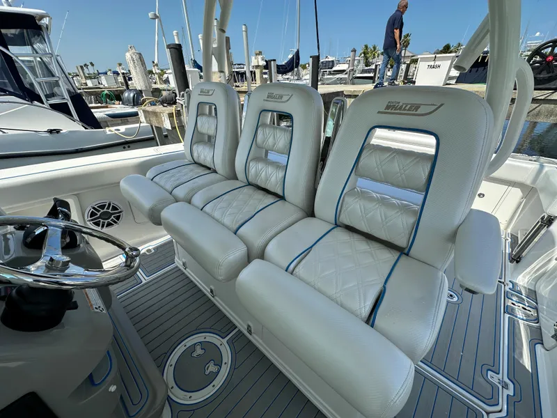 Slide: The Image of Drei luxuriöse, gepolsterte Sitze auf einem Boot, mit Steuerrad und Hafen im Hintergrund. - 26