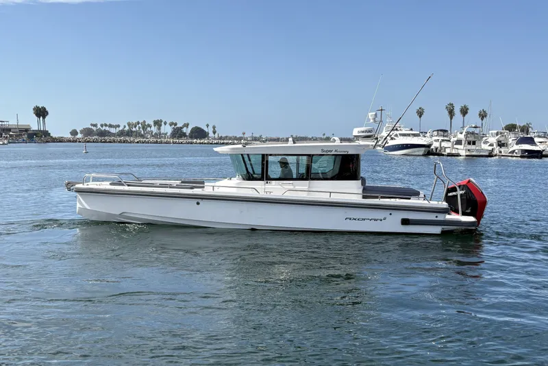 Slide: The Image of 2021 Axopar 28 Cabin on calm water, surrounded by yachts and palm trees. - 1