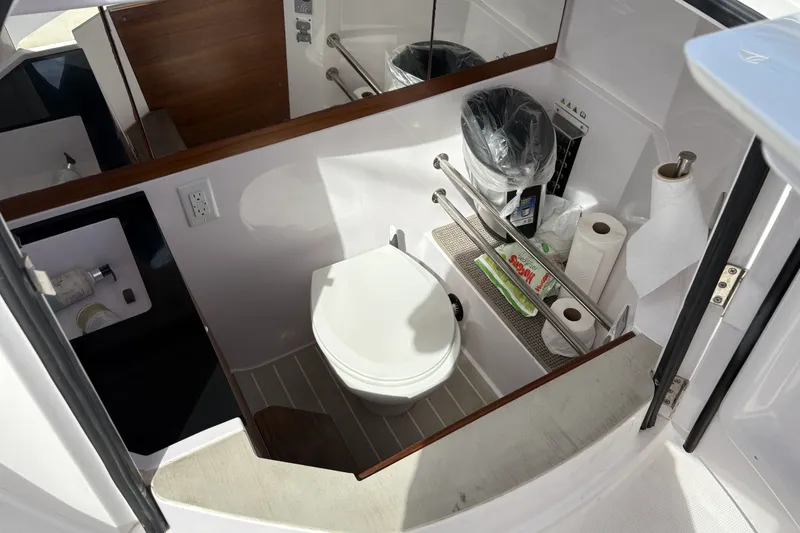 Slide: The Image of 2021 Axopar 28 Cabin bathroom with toilet, sink, and storage shelves. - 12