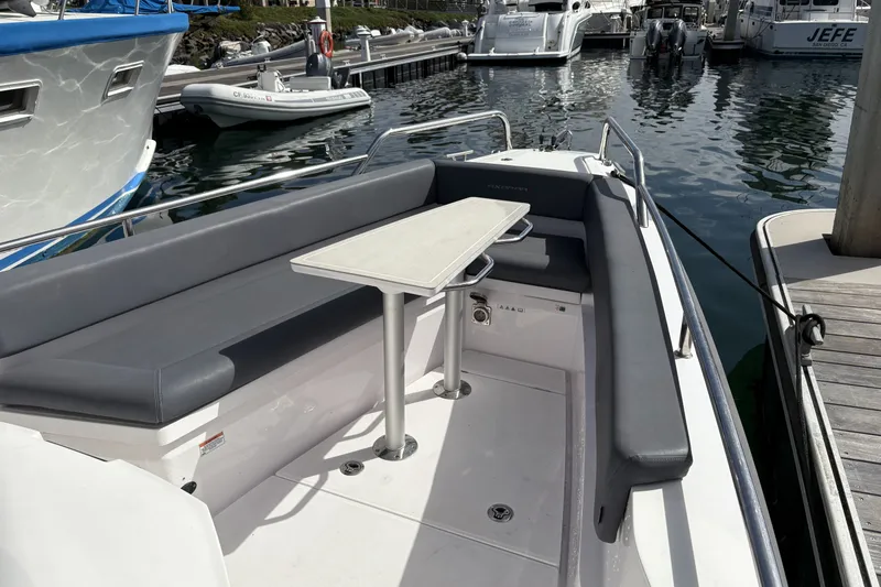 Slide: The Image of 2021 Axopar 28 Cabin boat interior with seating and table at marina. - 11