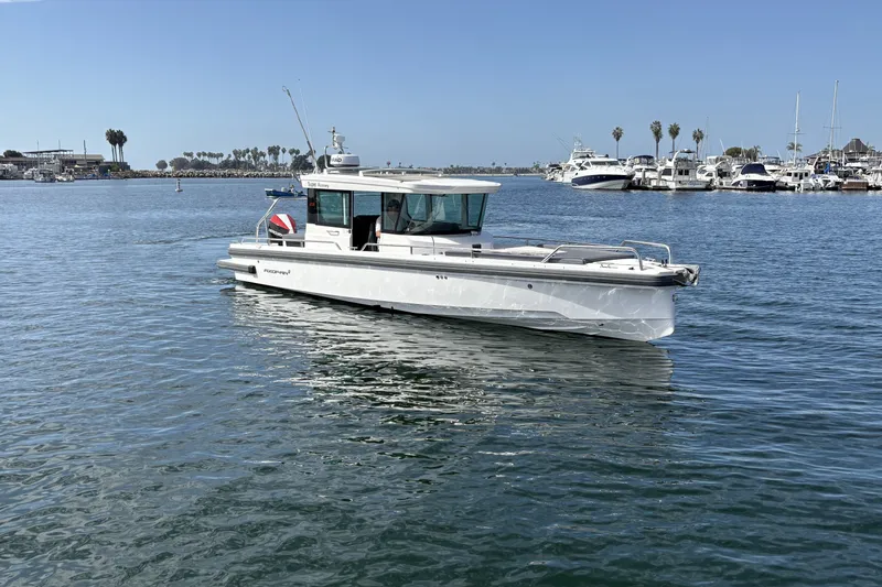 Slide: The Image of 2021 Axopar 28 Cabin boat cruising in a marina with clear blue skies. - 5