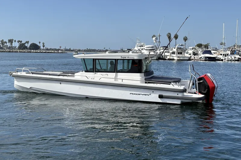 The Image of 2021 Axopar 28 Cabin boat cruising in a marina with clear skies. - 0