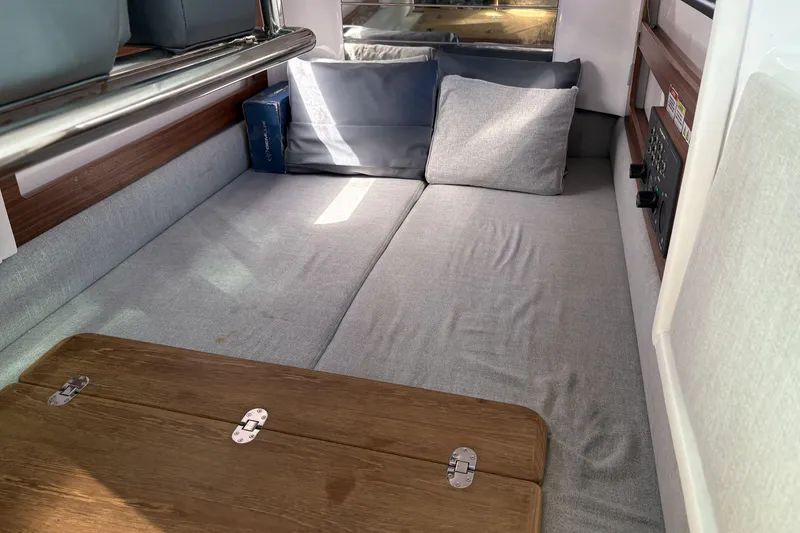 Slide: The Image of Cozy interior cabin of 2021 Axopar 28 Cabin with cushions and wooden table. - 10