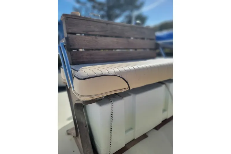 Slide: The Image of 1986 Boston Whaler 17 Montauk boat seat with wooden backrest and cushioned seating. - 16