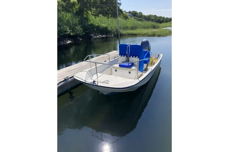 The Image of 1986 Boston Whaler 17 Montauk boat docked on calm water with blue seating. - 21