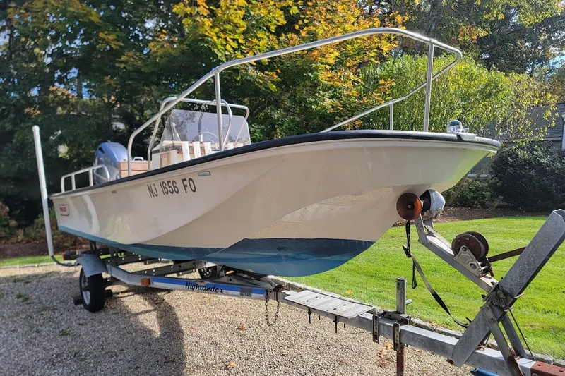 The Image of 1986 Boston Whaler 17 Montauk boat on trailer, surrounded by greenery. - 0