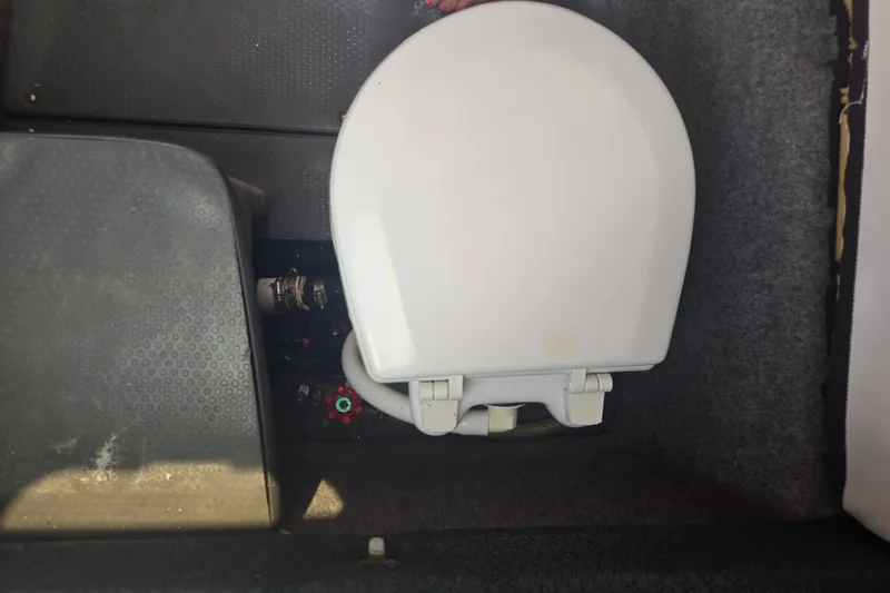 Slide: The Image of Boat toilet in a 2005 Trophy 2352 Walkaround, featuring a white seat and plumbing components. - 47