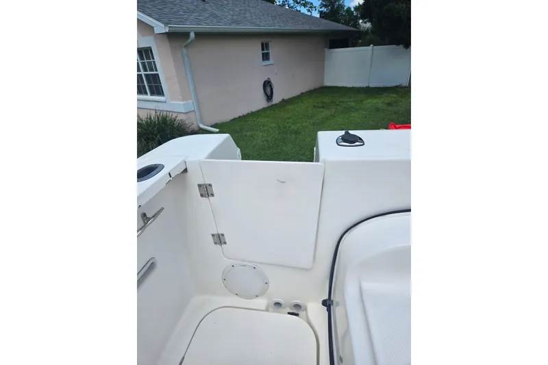 Slide: The Image of 2005 Trophy 2352 Walkaround boat interior near a house with green lawn. - 34