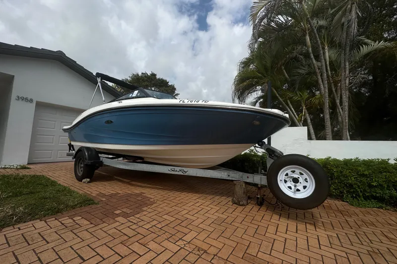 Slide: The Image of 2022 Sea Ray SPX 190 boat on trailer, parked in driveway near palm trees. - 7