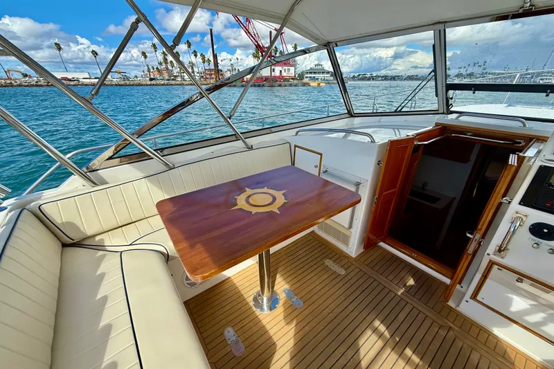 Slide: The Image of 1999 Grand Banks 38 Eastbay EX yacht interior with wooden table and seating, overlooking marina. - 14