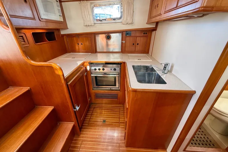 Slide: The Image of 1999 Grand Banks 38 Eastbay EX yacht kitchen with wood cabinetry, stainless steel sink, and oven. - 22