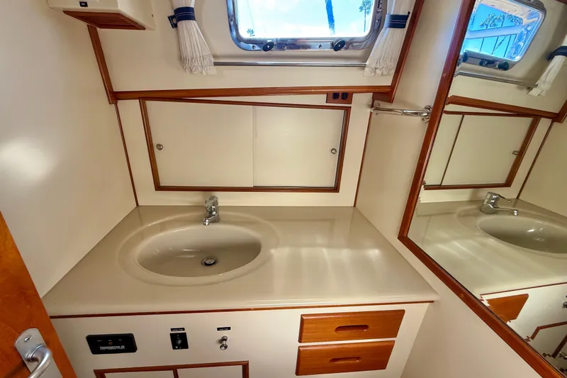 Slide: The Image of 1999 Grand Banks 38 Eastbay EX bathroom with sink, mirror, and storage cabinets. - 38