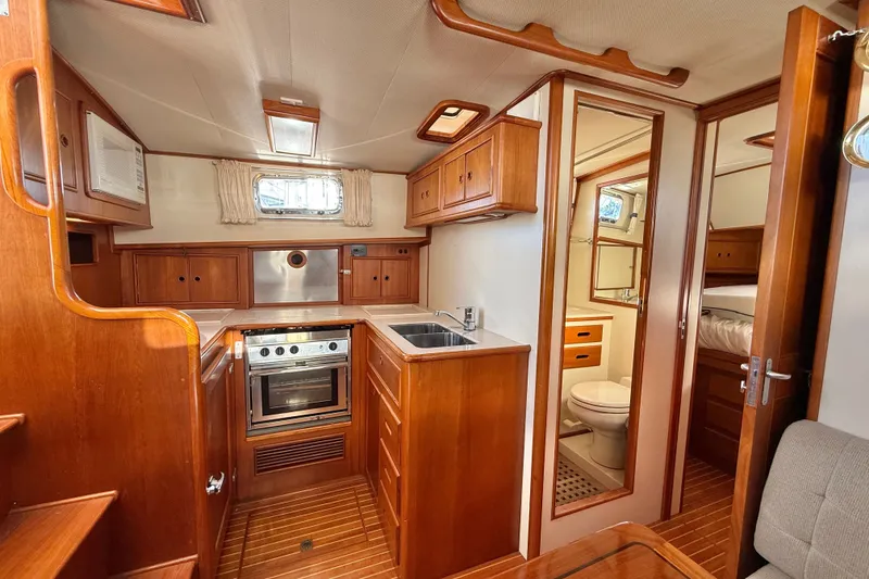 Slide: The Image of 1999 Grand Banks 38 Eastbay EX interior with wood cabinetry, kitchen, and bathroom. - 20