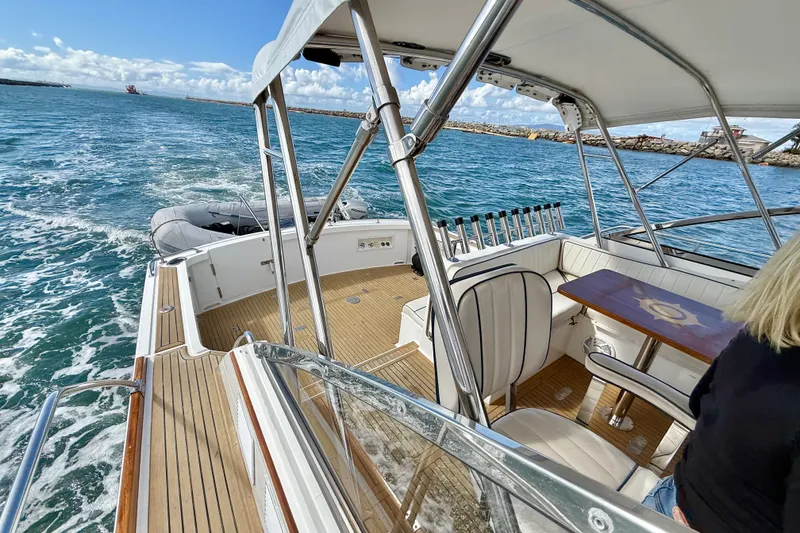 Slide: The Image of 1999 Grand Banks 38 Eastbay EX cruising on open water, featuring elegant seating and wooden deck. - 13