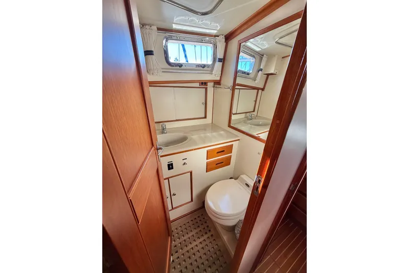 Slide: The Image of 1999 Grand Banks 38 Eastbay EX yacht bathroom with wood accents and porthole window. - 37